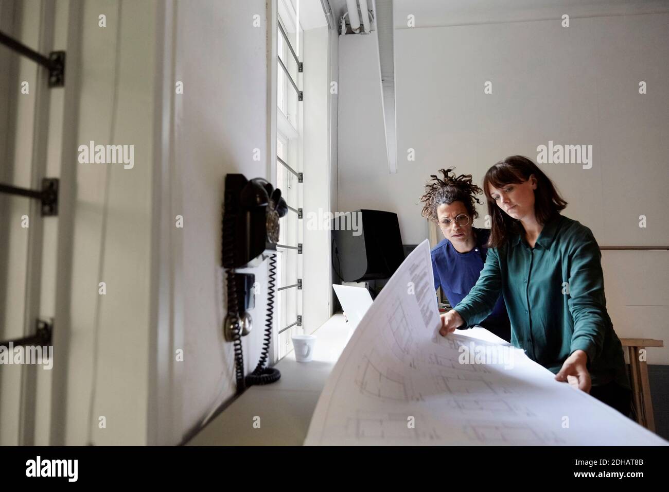 Architektin mit Blaupause am Tisch im Büro Stockfoto