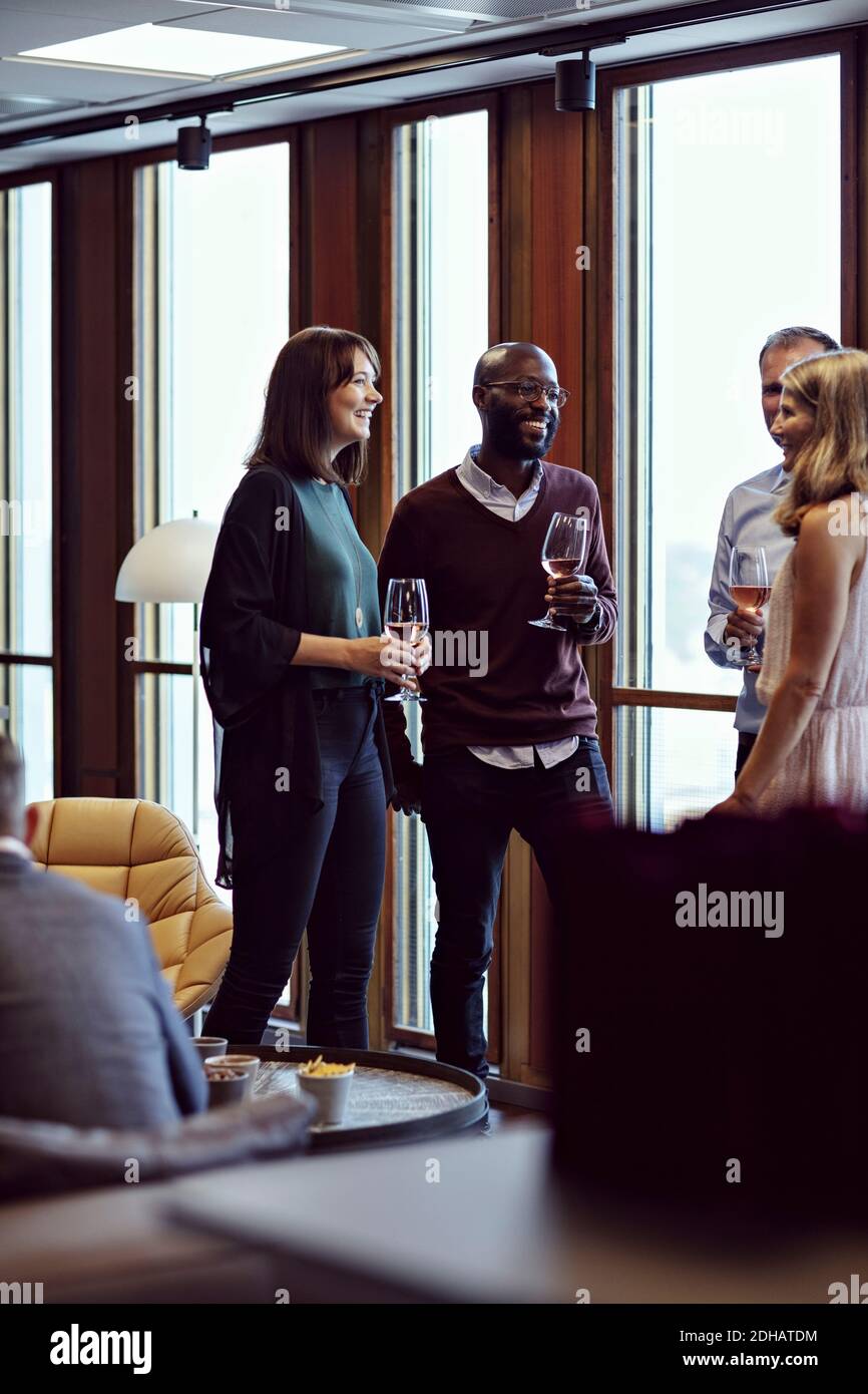 Lächelnde Geschäftsleute diskutieren bei einem Drink während der Konferenz im Büro Stockfoto