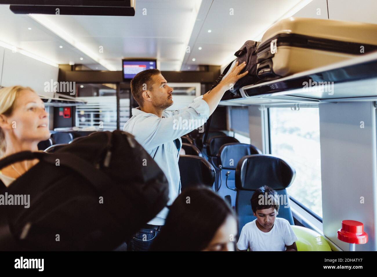 Mittelalter Mann, der Koffer im Zug auf dem Regal anordnete Familienurlaub Stockfoto