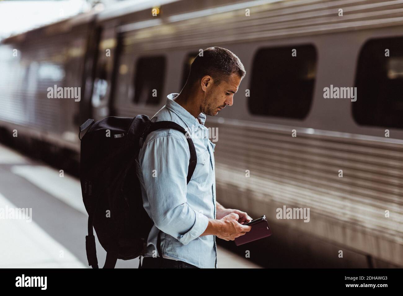 Tourist mit Rucksack mit Smartphone auf Bahnhofsplattform Stockfoto