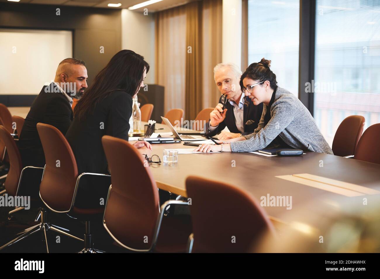 Männliche und weibliche Anwälte diskutieren über Dokument am Konferenztisch In Meetings Stockfoto