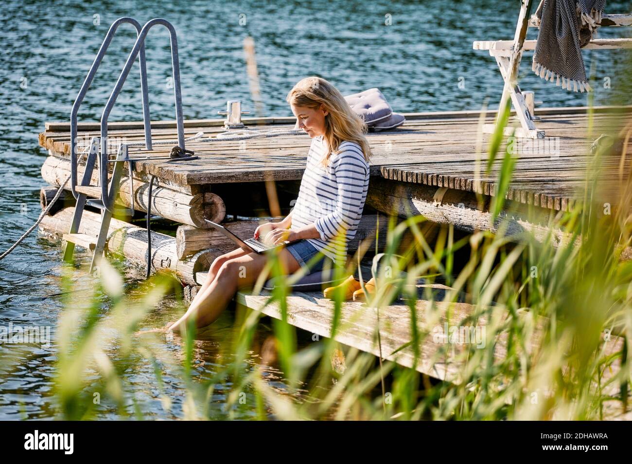Frau mittleren Erwachsenen mit Laptop während sitzen auf dem Steg während Sommer Stockfoto