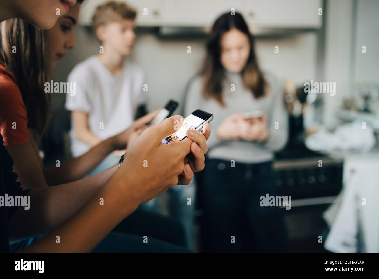 Nahaufnahme von Freunden mit Mobiltelefonen in der Küche Stockfoto