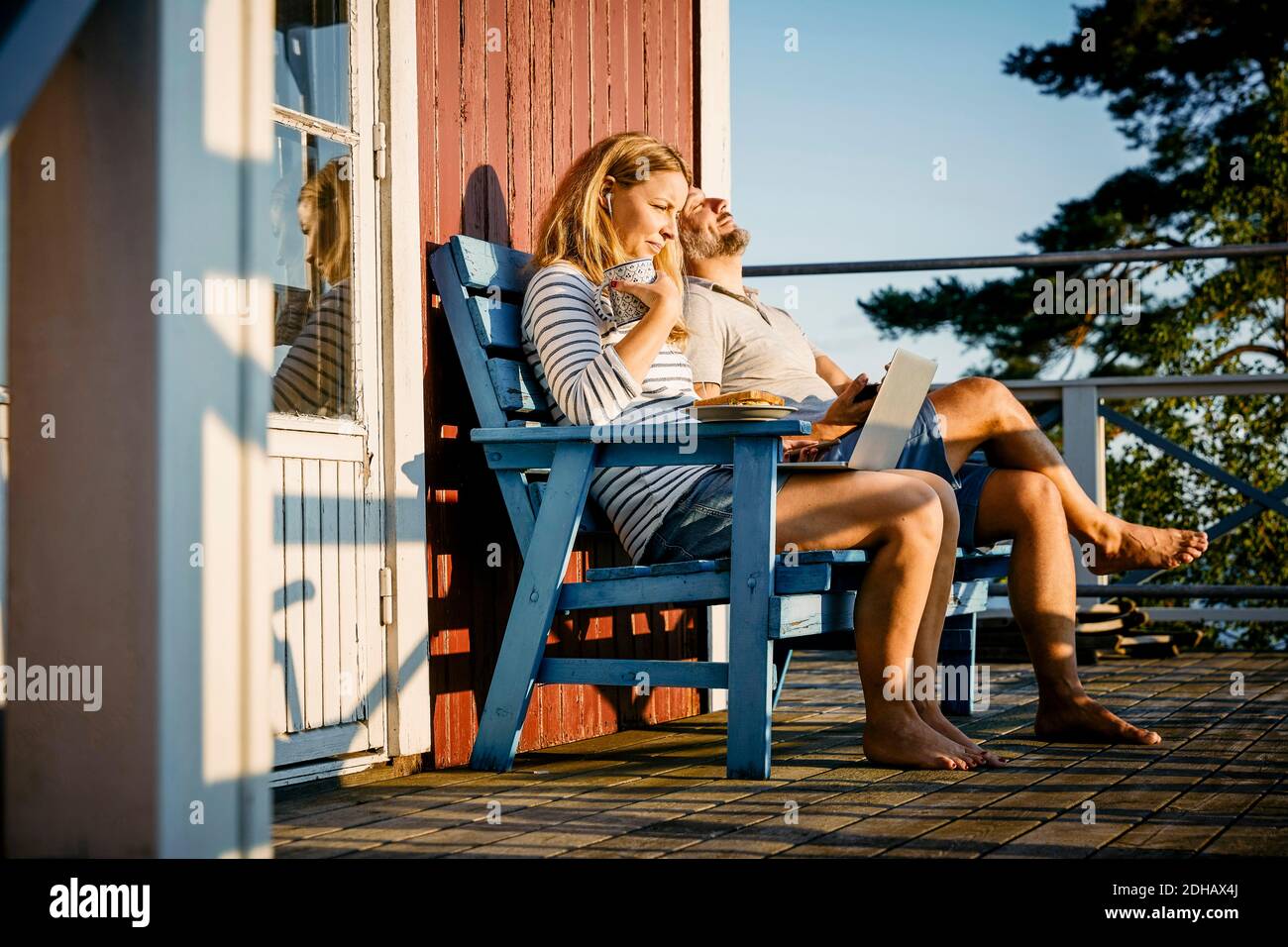 Frau mittleren Erwachsenen mit Laptop beim Frühstück und sitzen Mit Mann auf der Veranda Stockfoto