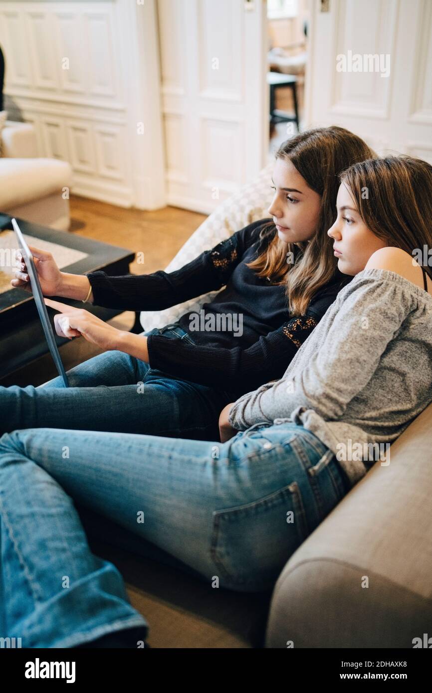 Mädchen mit Laptop, während sie zu Hause auf dem Sofa sitzen Stockfoto