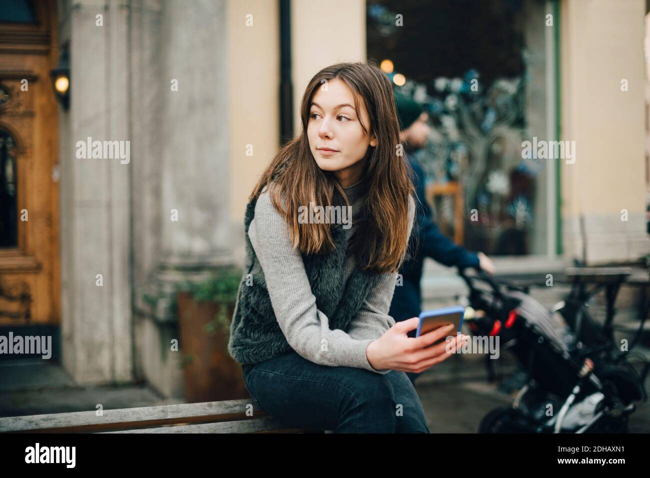 Nachdenklich Mädchen mit Smartphone auf Bank in der Stadt sitzen Stockfoto