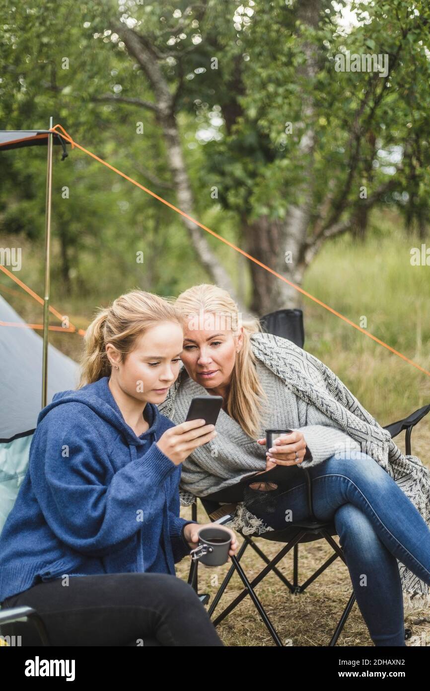 Mutter und Tochter beim Kaffee auf Smartphone schauen Auf dem Campingplatz Stockfoto