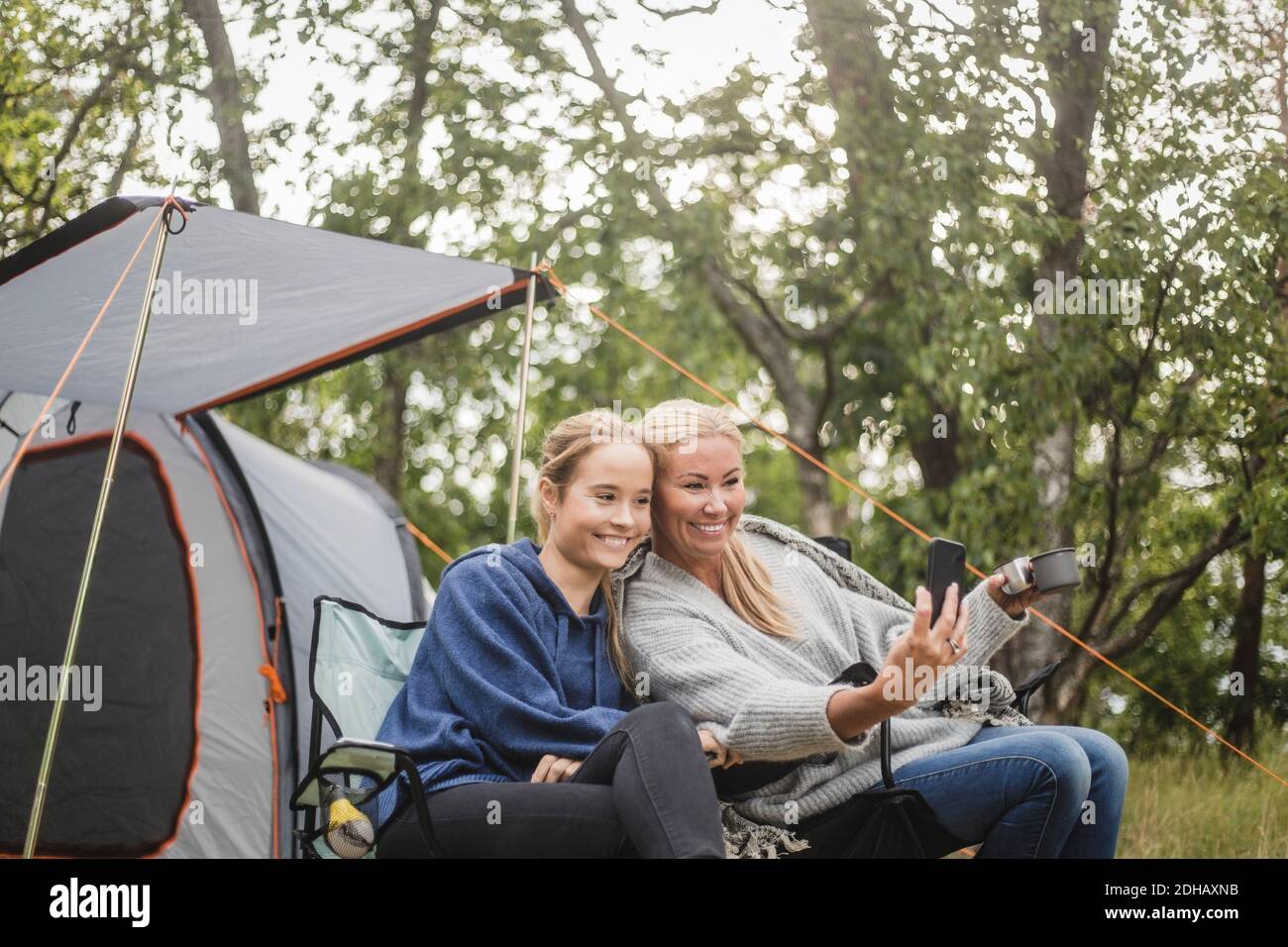 Glückliche Mutter nimmt Selfie mit Tochter auf Smartphone während Zeltcamping Stockfoto