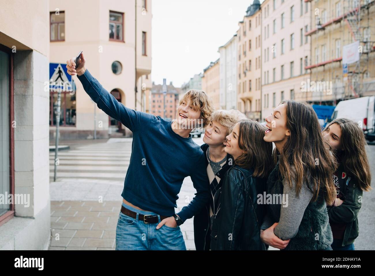 Männlich nimmt Selfie mit Freunden durch Smartphone im Stehen In der Stadt Stockfoto