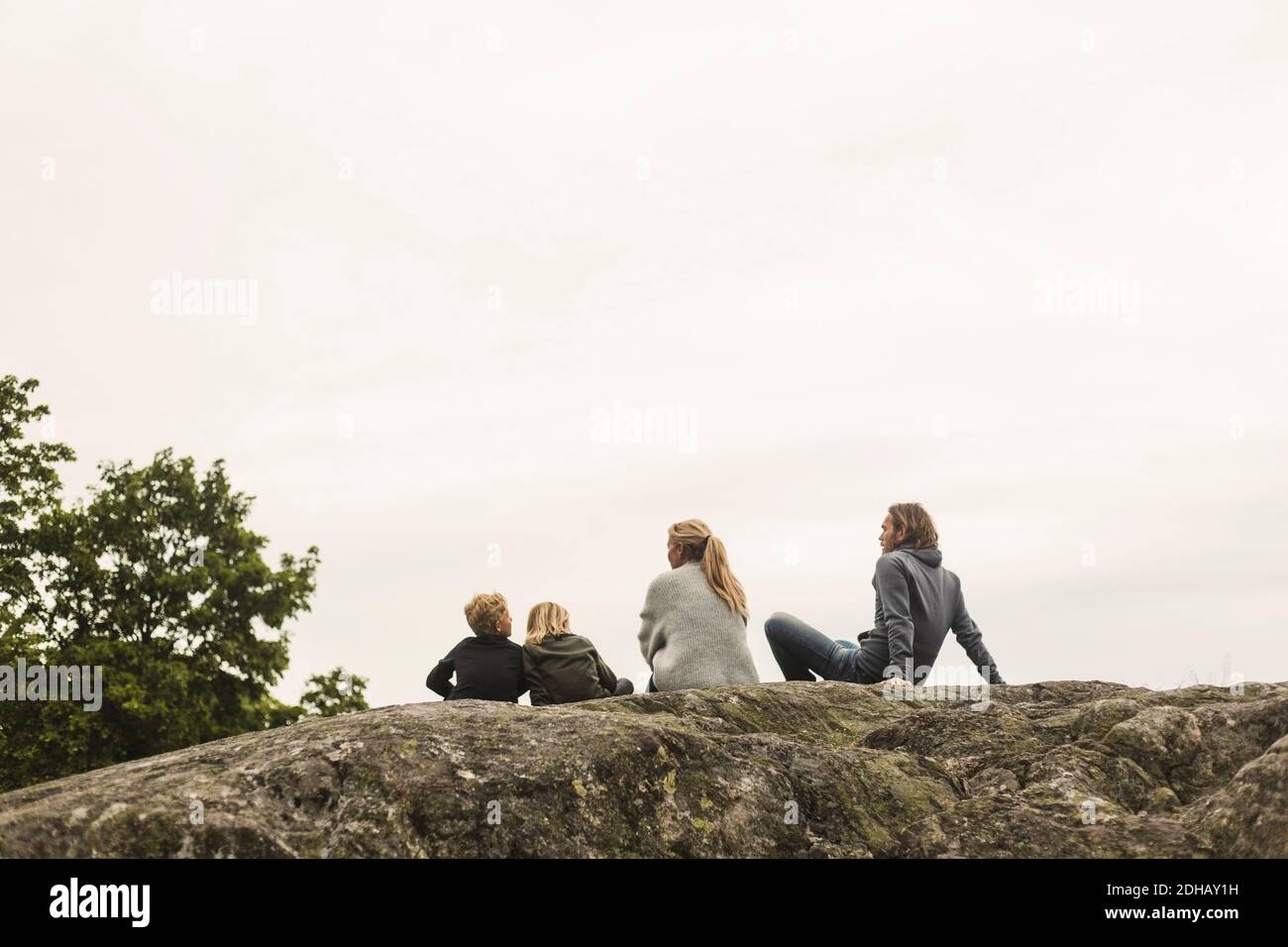Familie, die zusammen auf Felsformation gegen klaren Himmel ruht Stockfoto