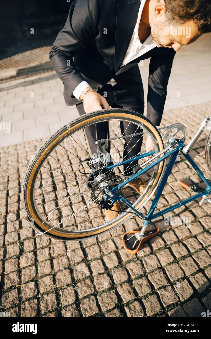 High-Angle-Ansicht des Geschäftsmannes Reparatur Fahrrad auf Fußweg in Stadt Stockfoto