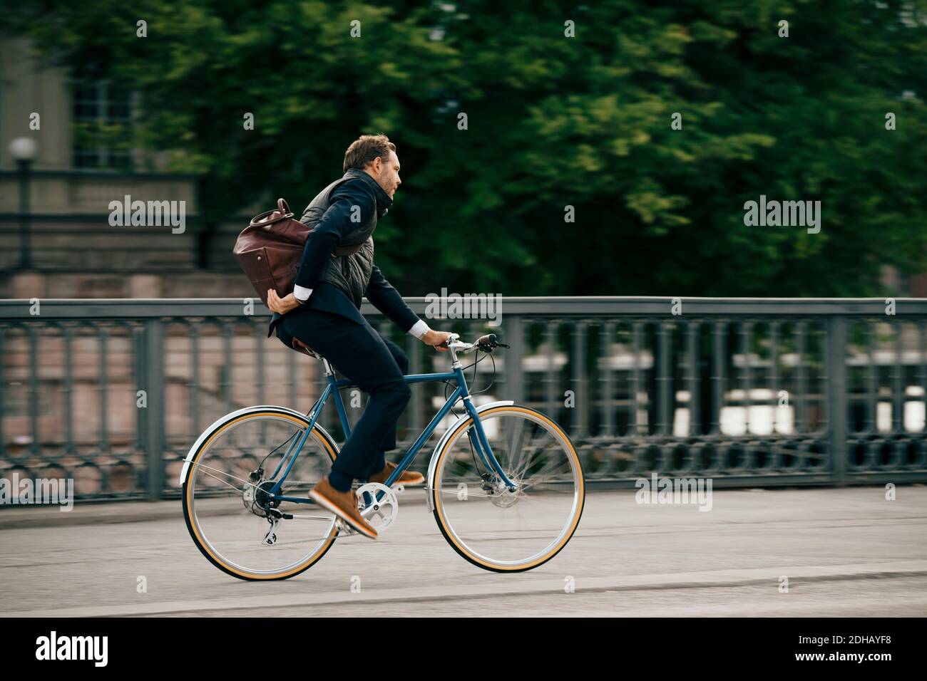 Seitenansicht des Geschäftsmannes mit Fahrradtasche auf der Brücke Stockfoto