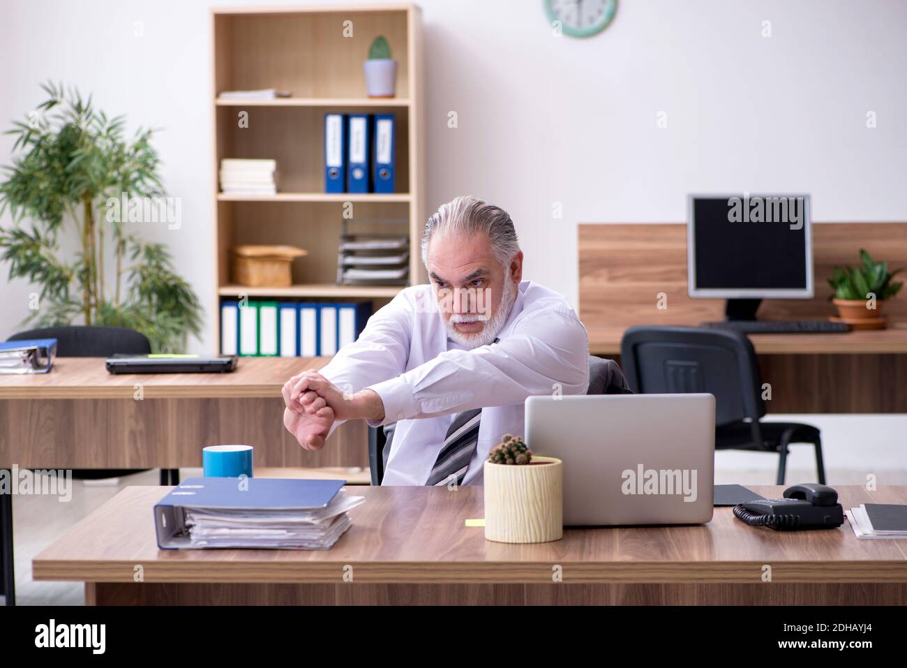Alter männlicher Mitarbeiter, der am Arbeitsplatz an einer Radikulitis leidet Stockfoto