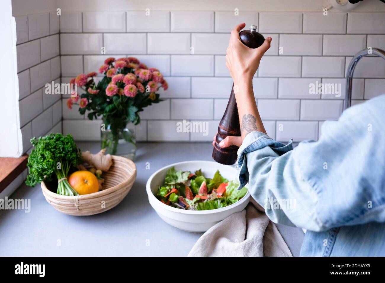 Zugeschnittenes Bild einer Frau, die Salat an der Küchentheke würzt Stockfoto