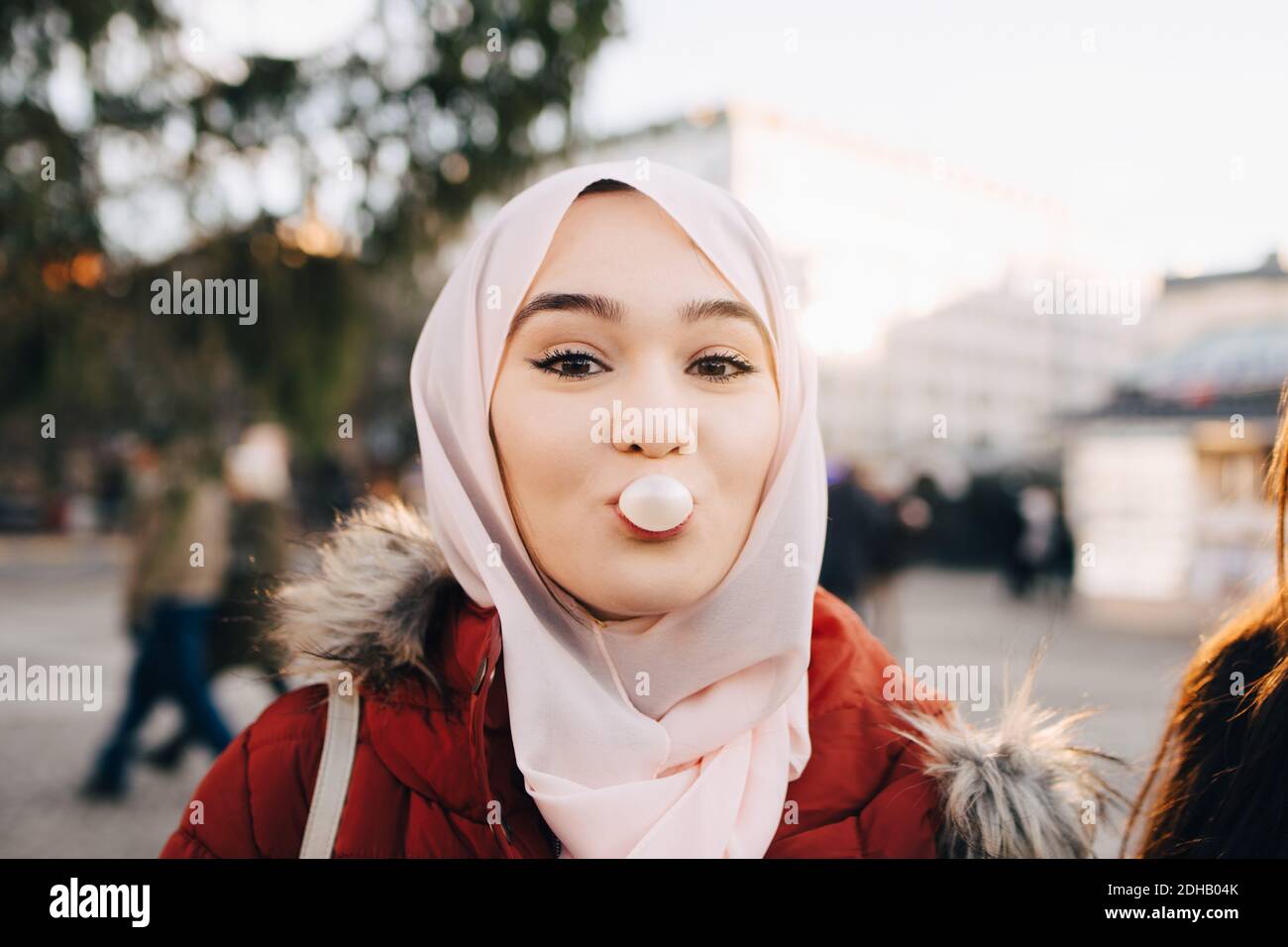 Portrait einer jungen muslimischen Frau, die in der Stadt Kaugummi bläst Stockfoto