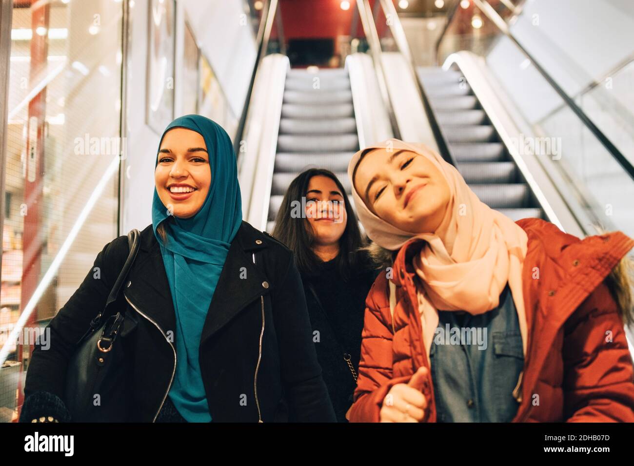 Portrait von glücklichen Freundinnen auf Rolltreppe im Einkaufszentrum Stockfoto