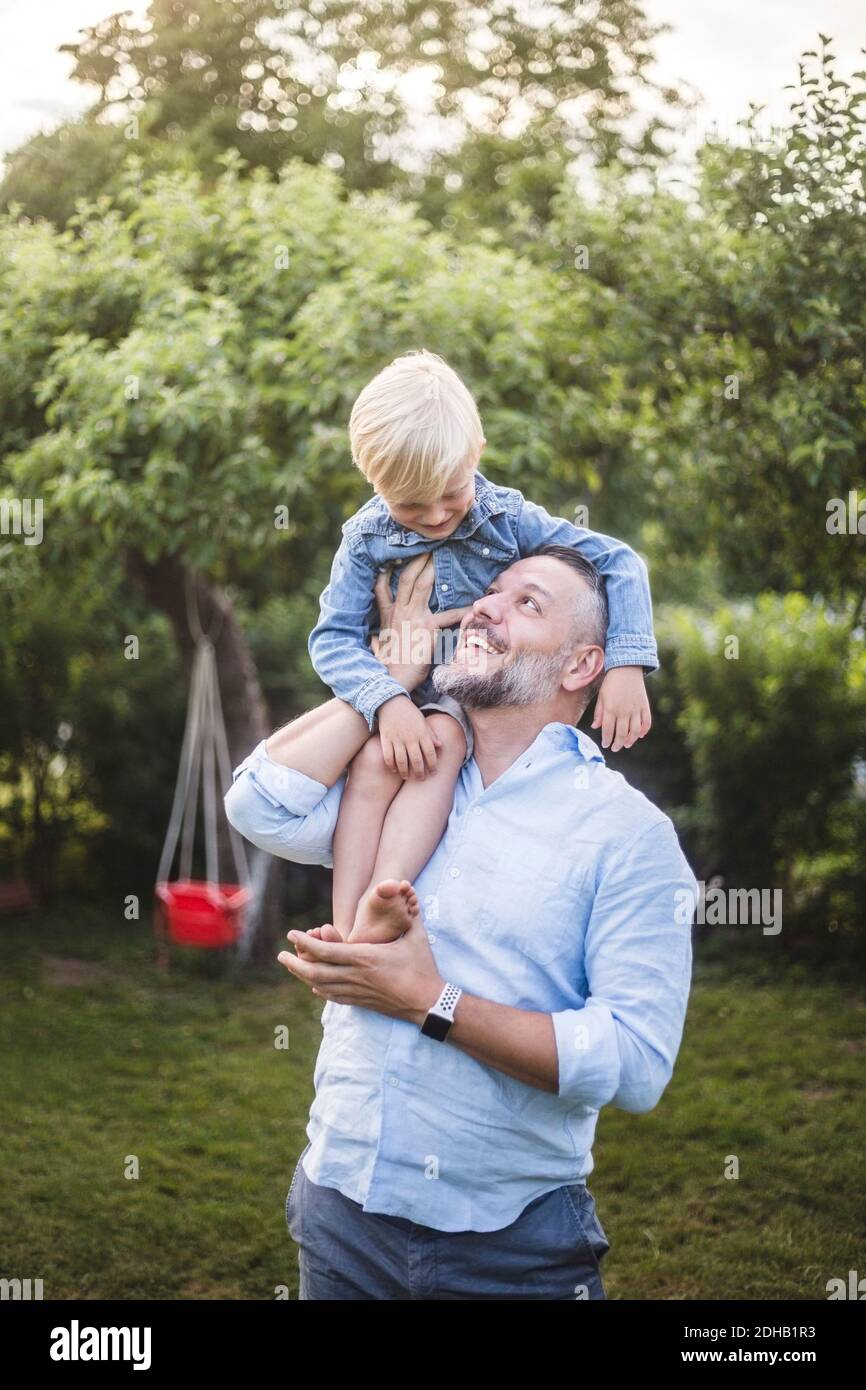 Glücklicher Vater trägt Sohn auf Schultern im Hinterhof Stockfoto