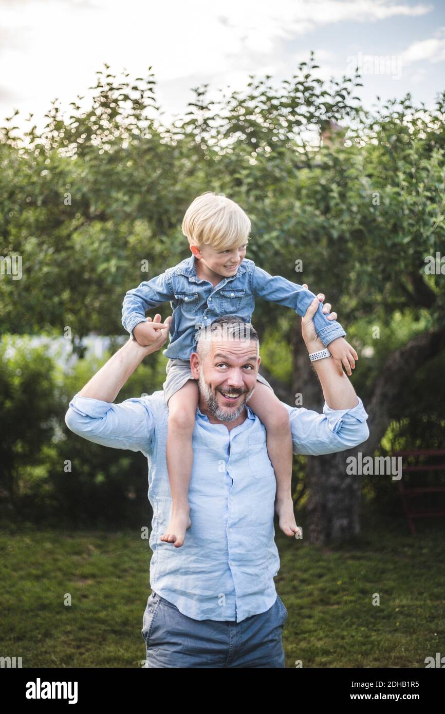 Vater trägt Sohn auf Schultern im Hof, während Sie den Sommer genießen Wochenende Stockfoto