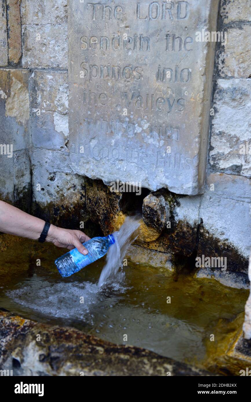 Nachfüllen einer Einweg-Plastikflasche mit Wasser an einer natürlichen Quelle mit Aufschrift oben über Quellen, Täler und Hügel, Zypern. Inschrift „Die Stockfoto