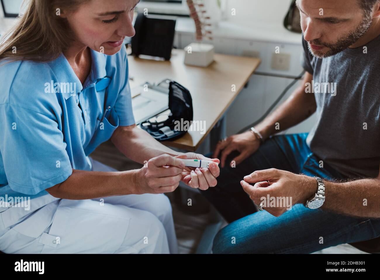 Ansicht der Krankenschwester, die medizinische Geräte hält, während sie erklärt An den Patienten in der Klinik Stockfoto