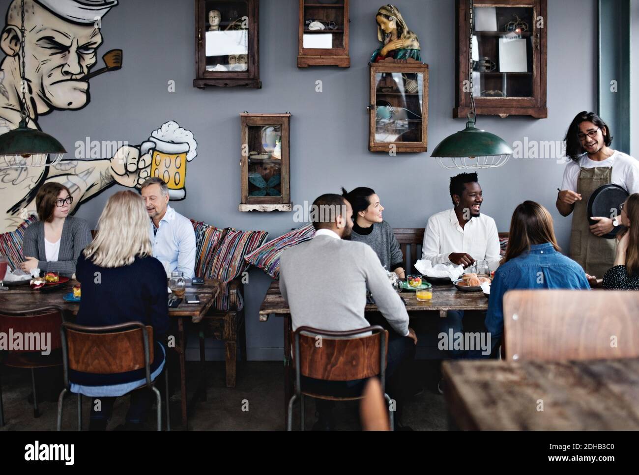 Der Besitzer sprach mit multiethnischen Freunden während der Familie beim Brunch Tisch im Restaurant Stockfoto