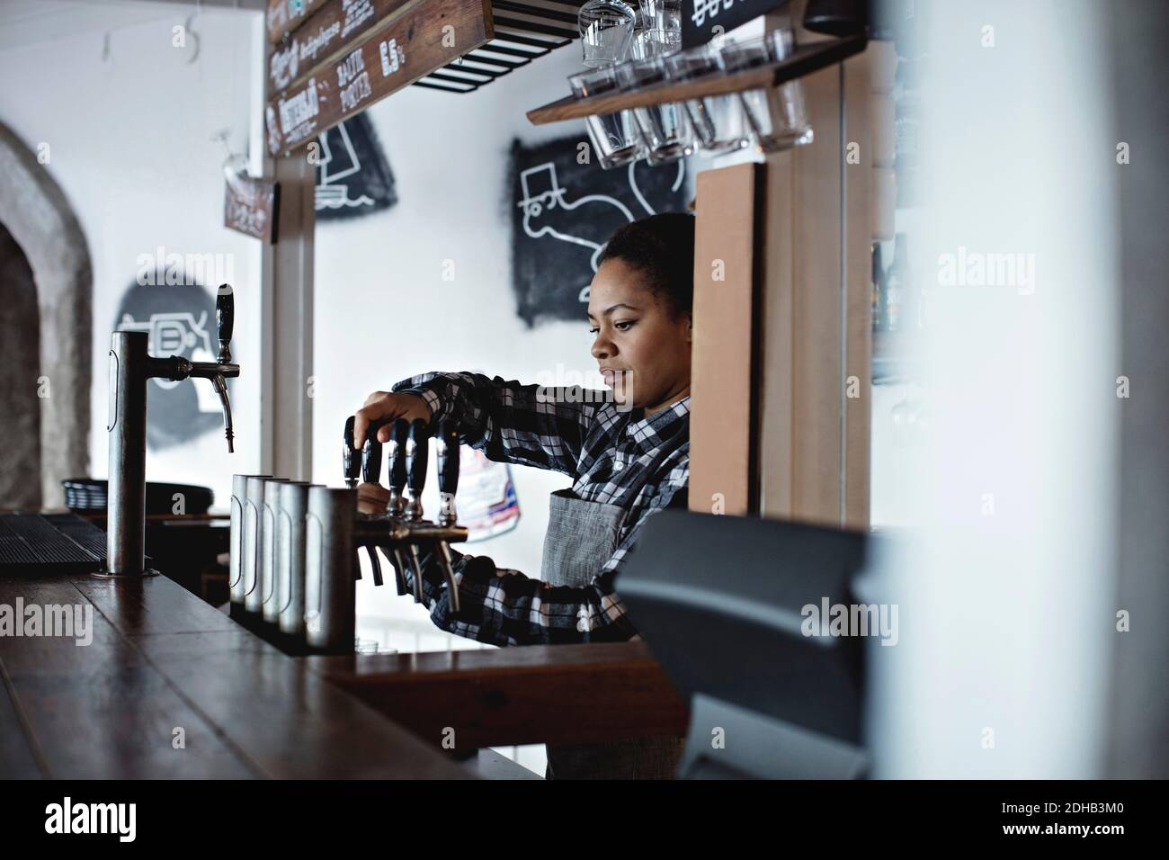 Weibliche Barkeeperin gießt Bier vom Fass im Restaurant Stockfoto