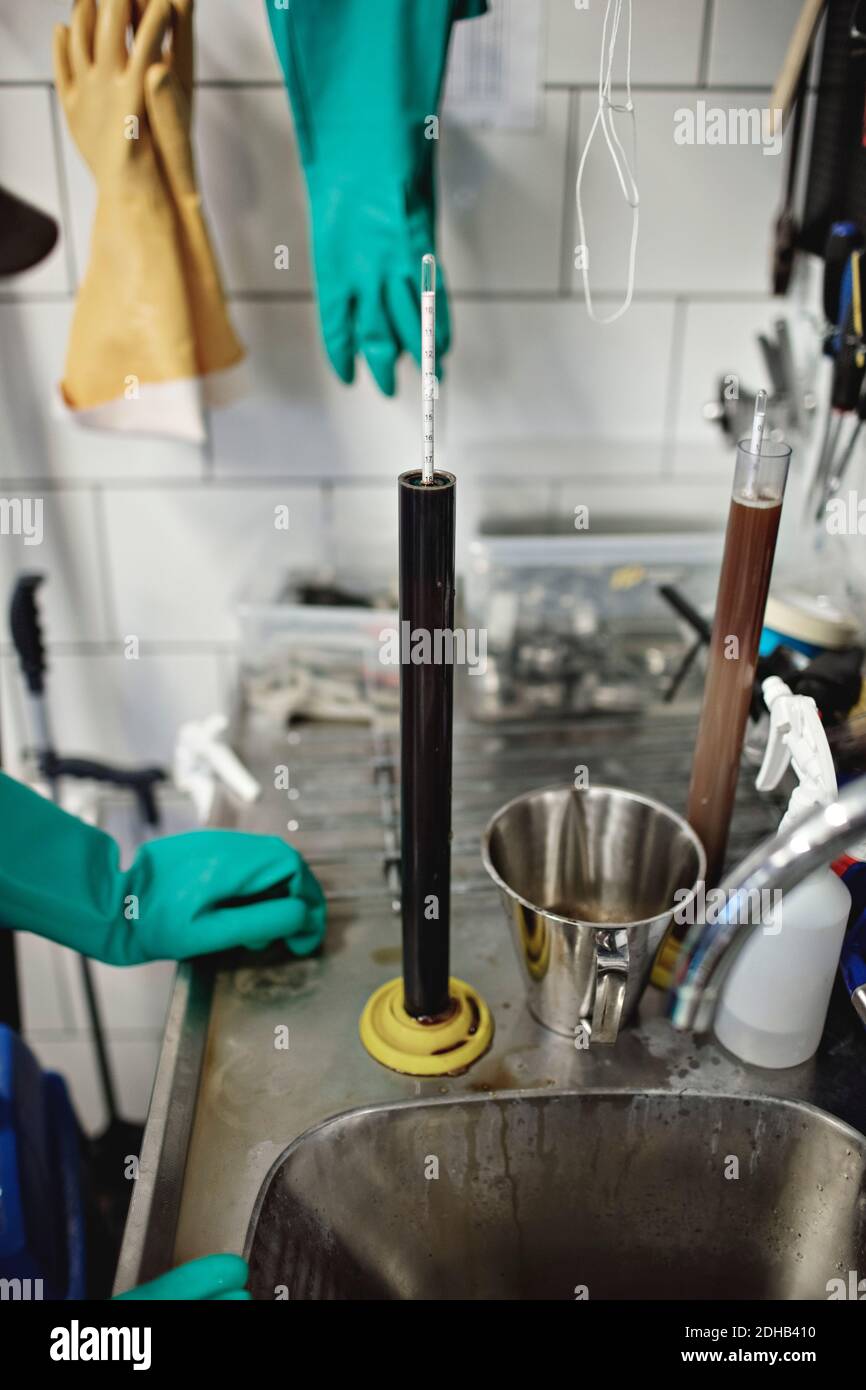 Zugeschnittenes Bild des Arbeiters, der bei Bechergläsern mit Thermometern steht Brauerei Stockfoto