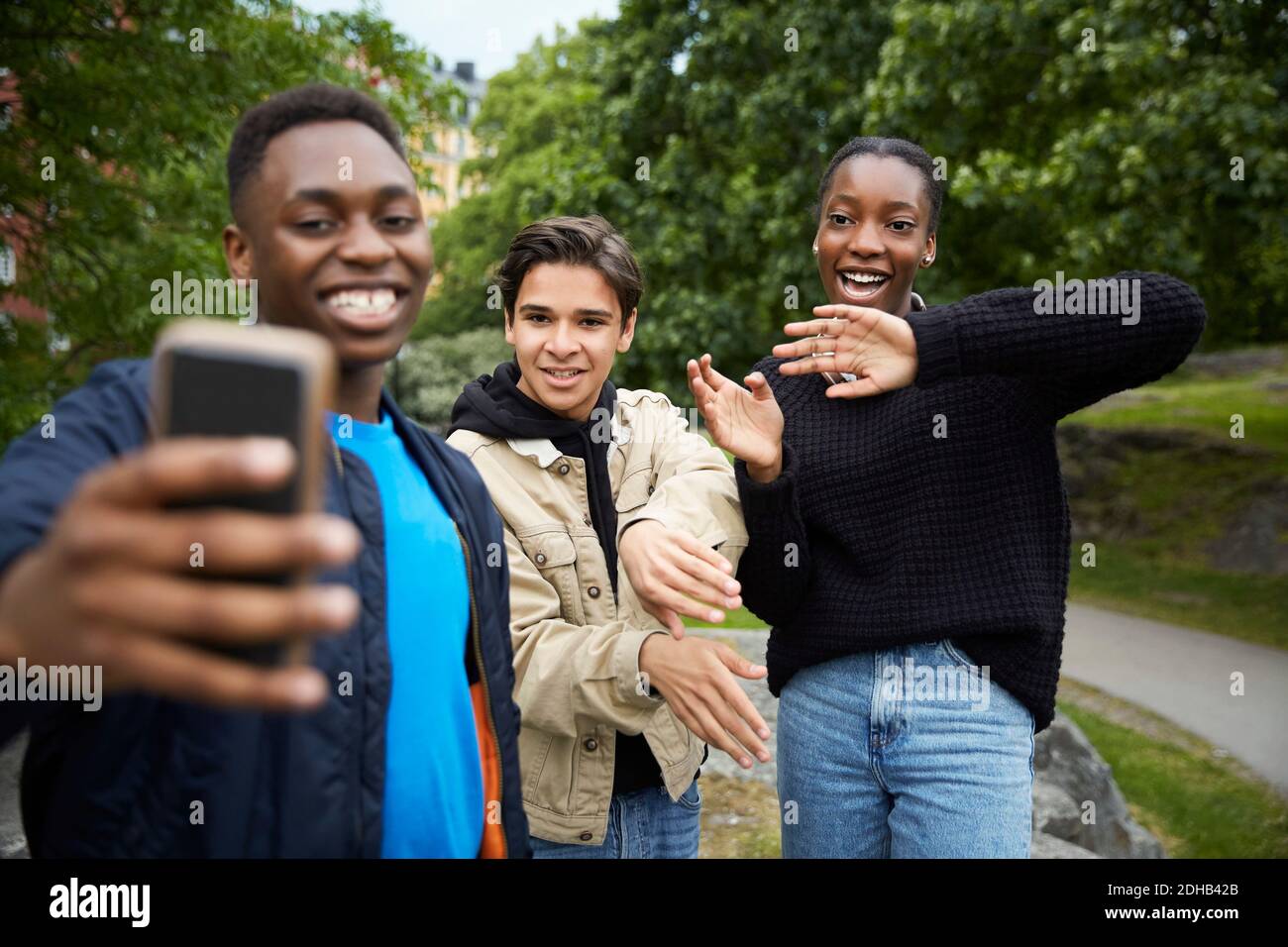 Glückliche Freunde, die beim Tanzen auf das Smartphone schauen parken Stockfoto