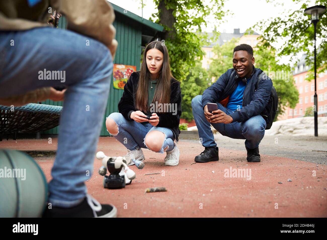 Freunde steuern Roboter mit Smartphone, während mit Kampf an parken Stockfoto