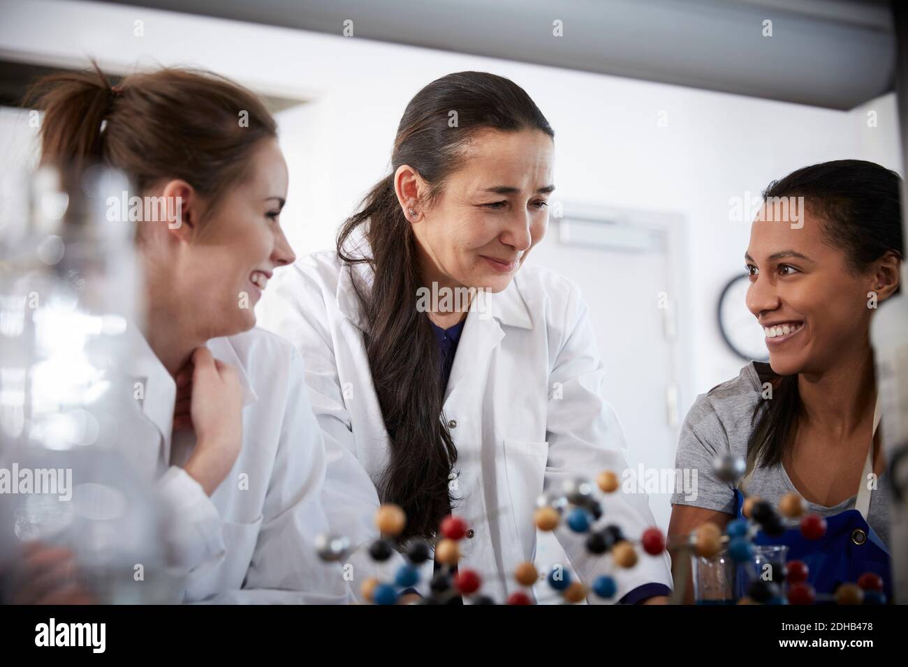 Lächelnd reife Chemielehrerin mit jungen Schülerinnen im Klassenzimmer An der Universität Stockfoto