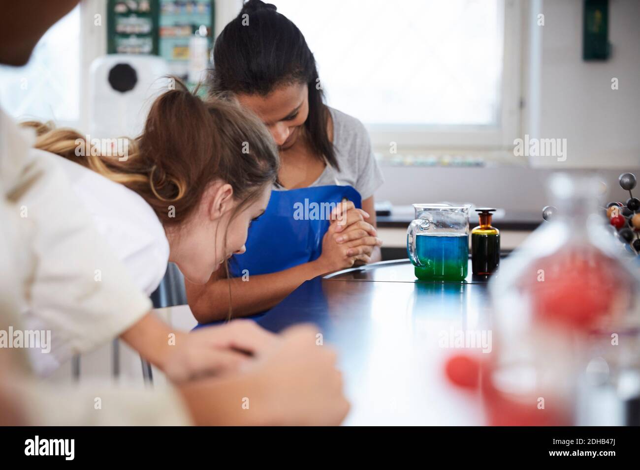 Studentinnen, die sich mit flüssiger Lösung im Becherglas in der Chemie befrechen Labor Stockfoto