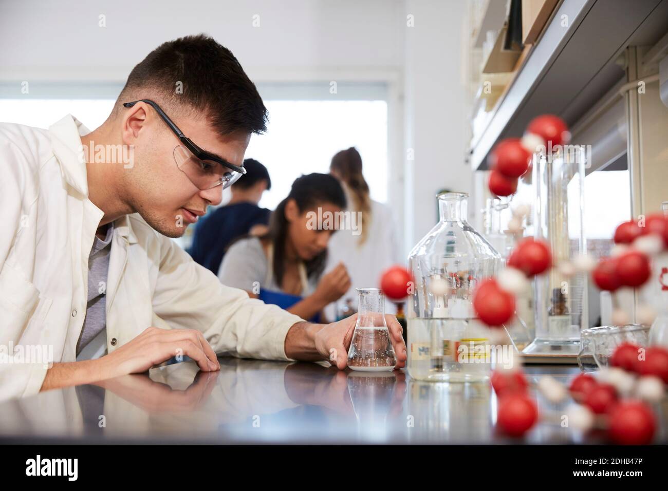 Zuversichtlich junge männliche Chemie-Student von Freunden im Labor an universität Stockfoto