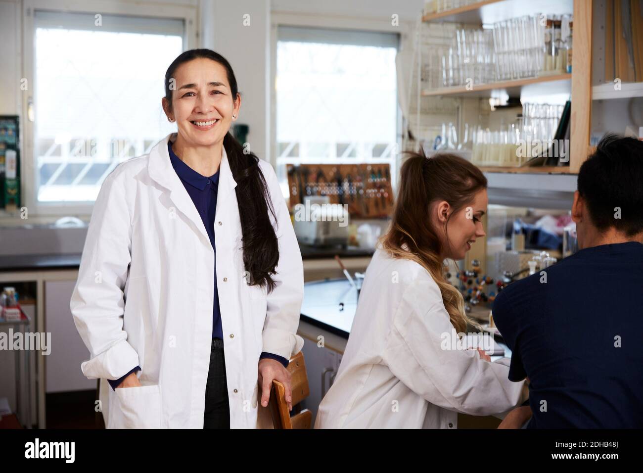 Porträt einer selbstbewussten reifen weiblichen Chemielehrerin, die bei den Schülern steht Im Labor an der Universität Stockfoto