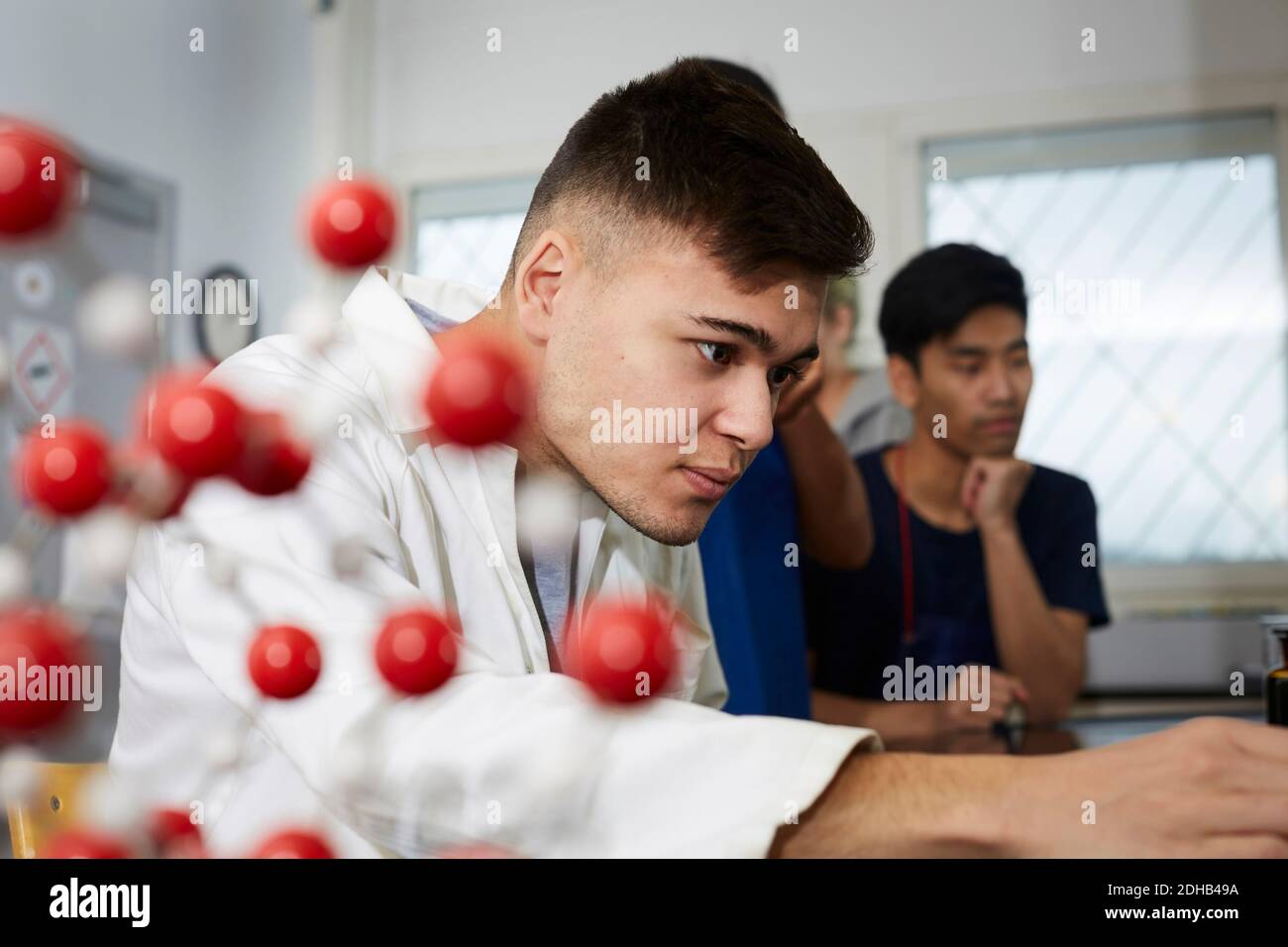 Selbstbewusster junger Chemiestudent von Freunden im Klassenzimmer Stockfoto