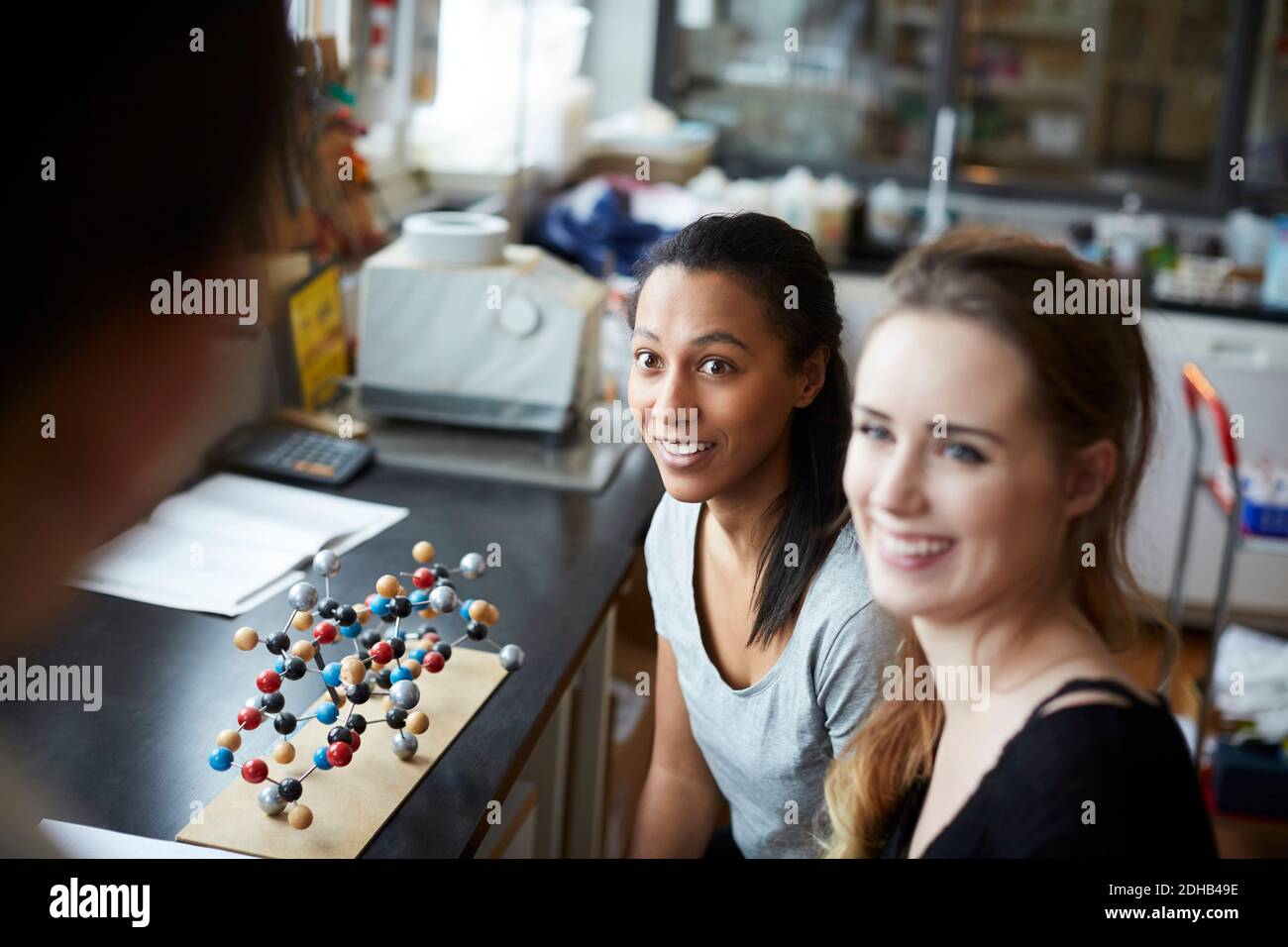 Lächelnd junge Studentinnen durch molekulare Struktur Blick auf reifen Lehrer im Chemie-Klassenzimmer Stockfoto