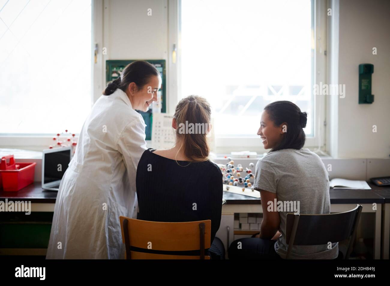 Lächelnder reifer Chemielehrer mit jungen Schülern im Klassenzimmer Stockfoto
