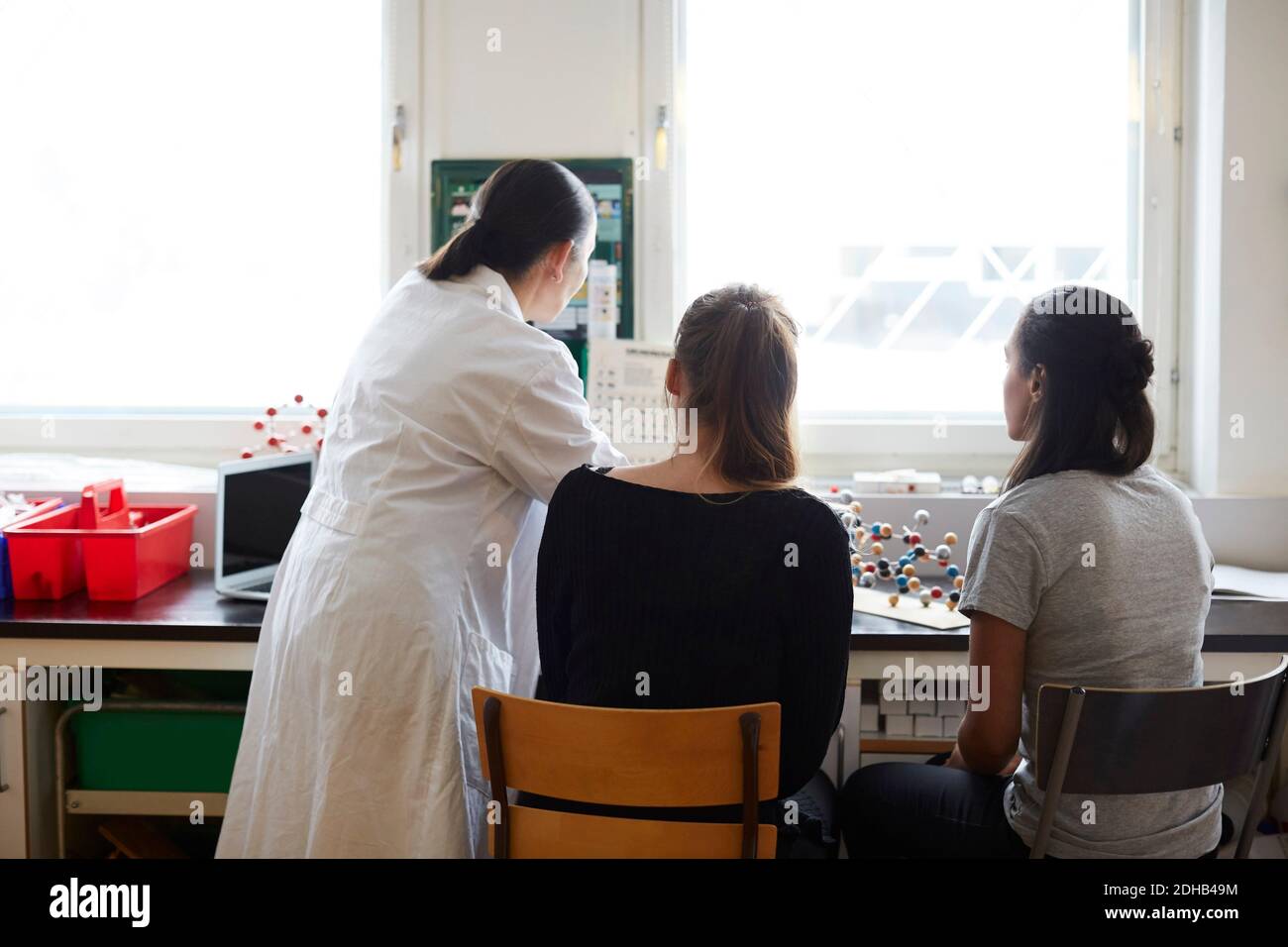 Rückansicht des reifen Chemielehrers mit jungen Schülern in Schulungsraum Stockfoto