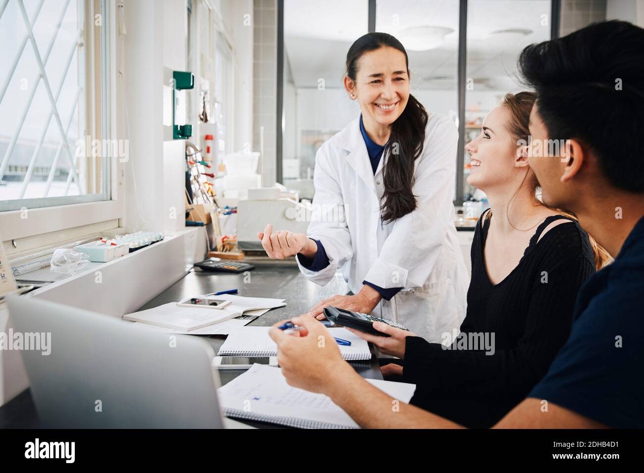 Lächelnd reife Lehrerin erklärt multiethnischen jungen Ingenieurstudenten Im Klassenzimmer der Universität Stockfoto