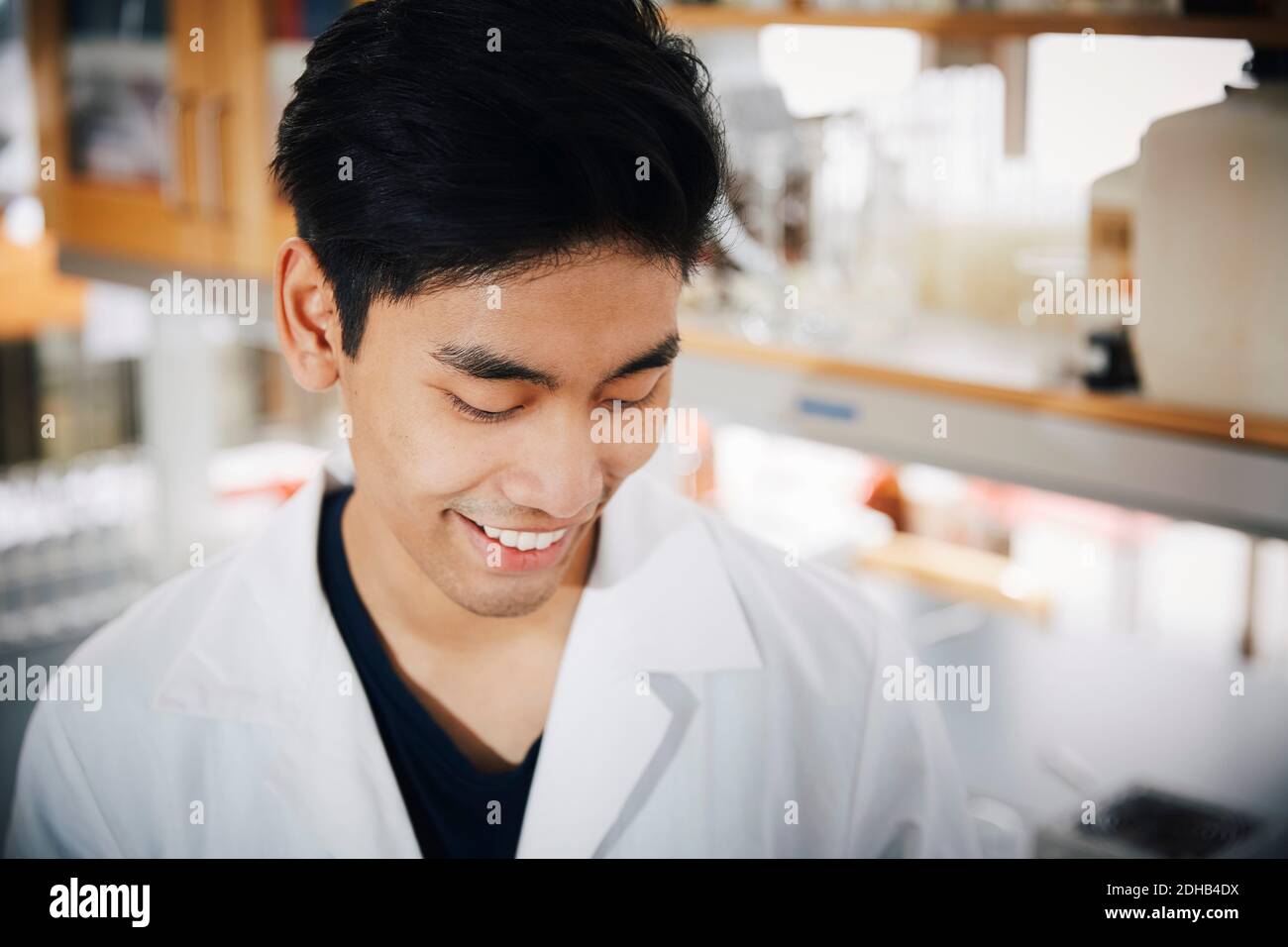 Lächelnder junger männlicher Universitätsstudent, der auf das Chemielabor herabschaut Stockfoto