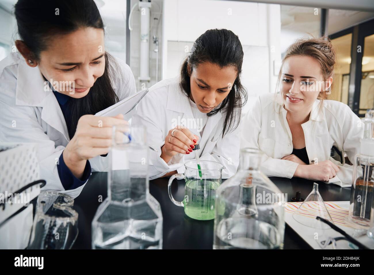 Reife Chemie Lehrer suchen an jungen Studenten mischen Flüssigkeit Lösung im Becher Stockfoto