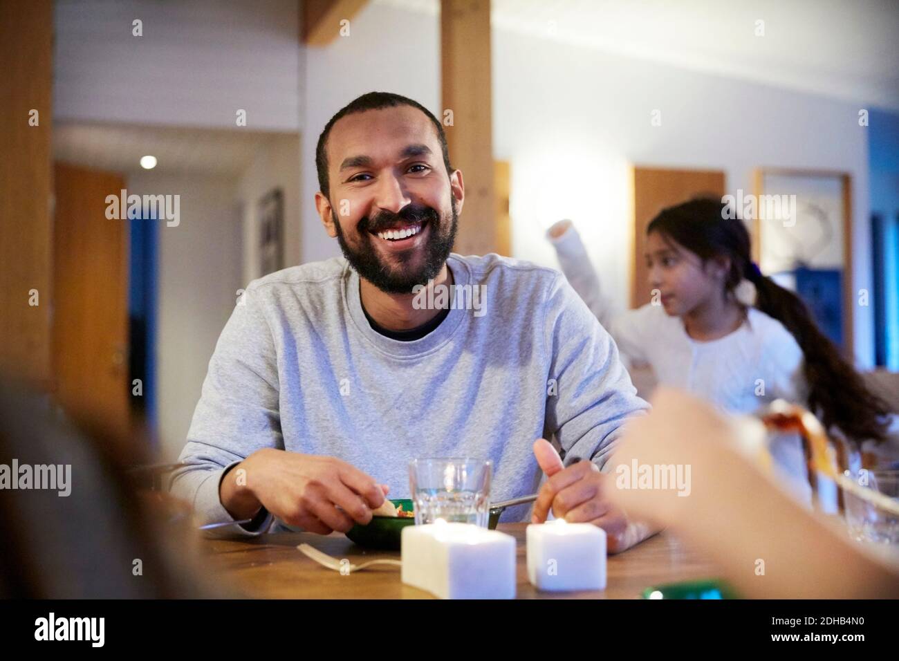Lächelnder Mann, der mit der Familie zu Hause Essen hat Stockfoto