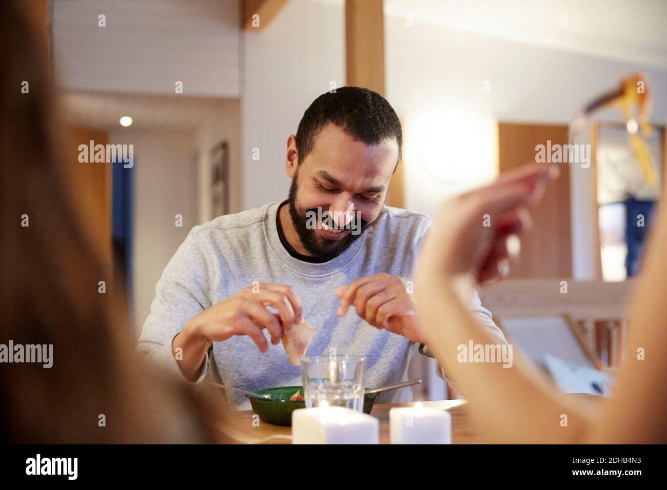 Lächelnder Mann beim Essen mit Familie am Tisch Stockfoto