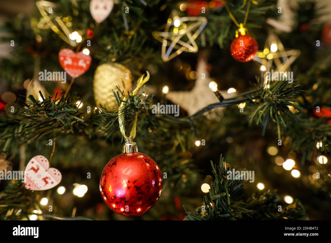 Bild mit geringer Schärfentiefe (selektiver Fokus) mit einem roten Ornament in einem Weihnachtsbaum aus Kunststoff. Stockfoto
