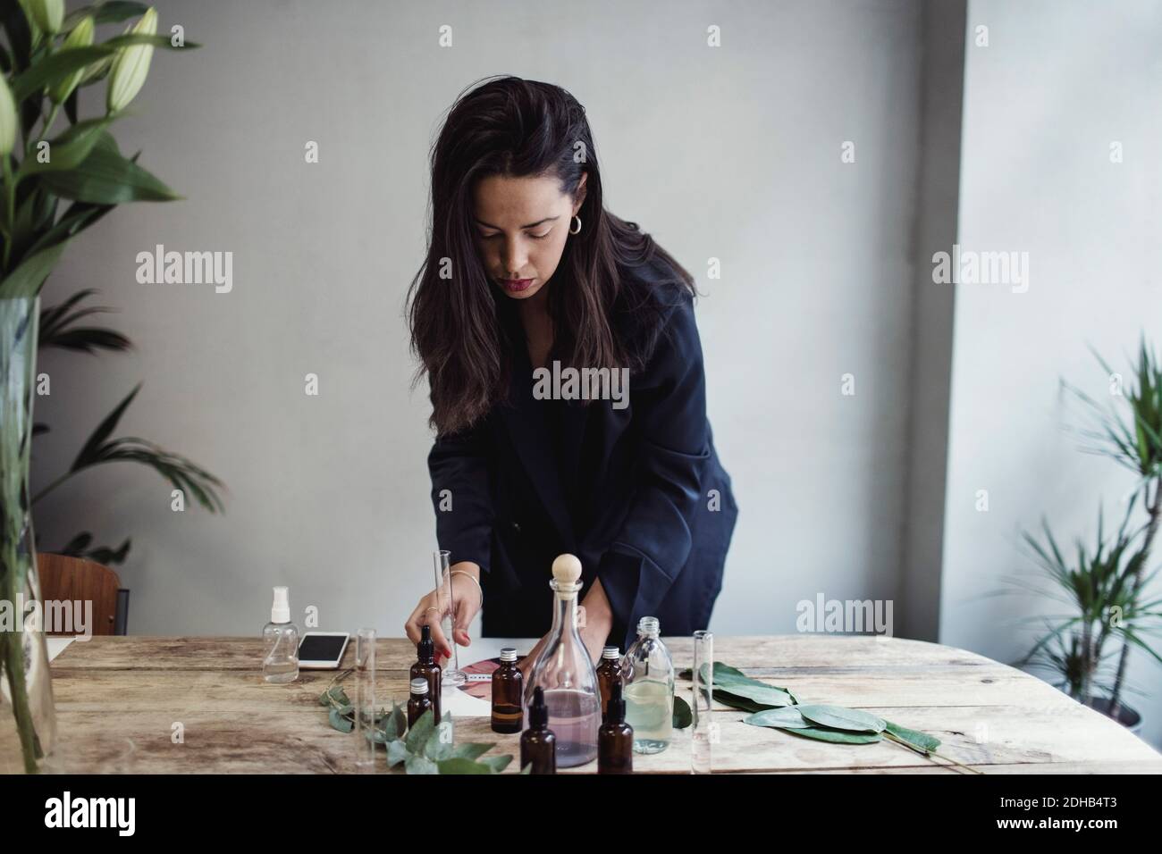 Mid adult weibliche Unternehmerin Vorbereitung Parfüm auf Tisch gegen Wand In der Werkstatt Stockfoto