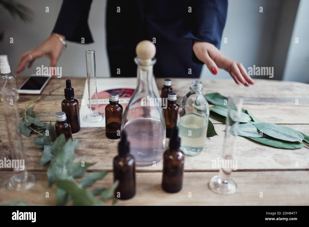 Mittelteil der mittleren erwachsenen Unternehmerin Vorbereitung Parfüm auf dem Tisch In der Werkstatt Stockfoto