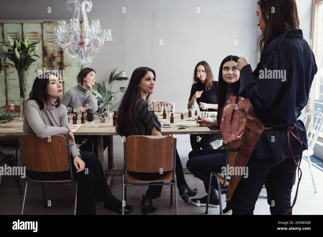 Multiethnische weibliche Kollegen, die die Inhaberin eines mittleren Erwachsenen betrachten, die darin steht Parfüm-Werkstatt Stockfoto
