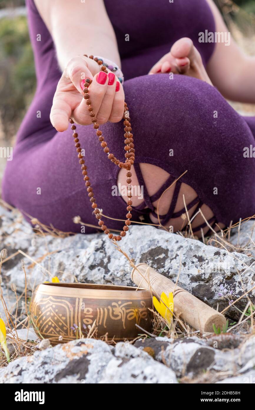 Yogi-Frau meditiert mit Rosenkranz und tibetischer Klangschale. Stockfoto