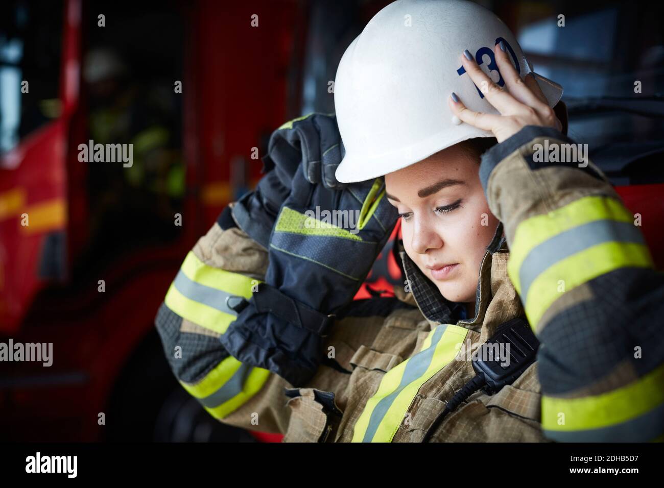 Feuerwehrfrau mit Helm beim Blick auf die Feuerwehr Stockfoto
