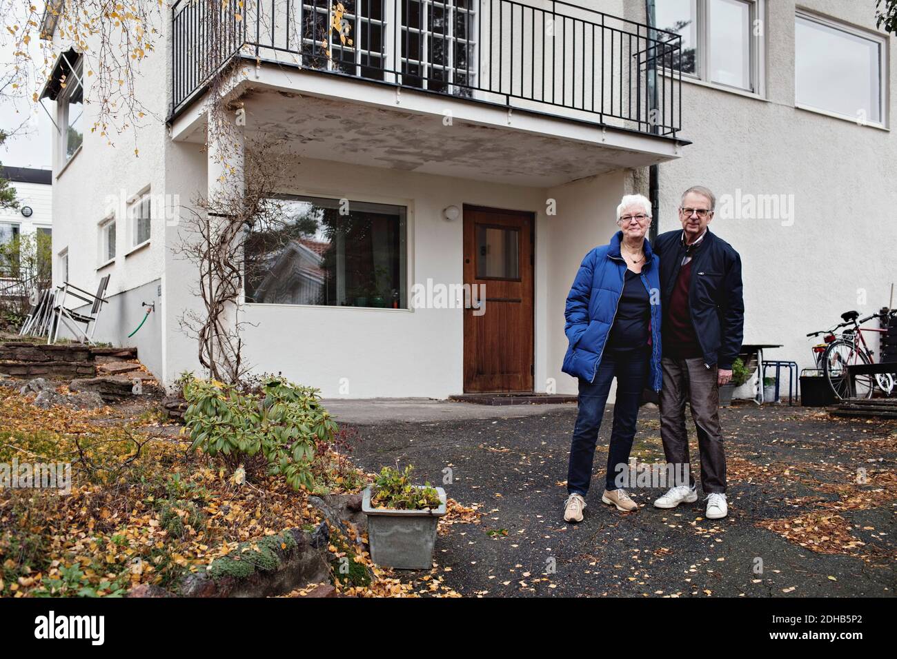 Full Länge Porträt des Rentnerehepaares stehend gegen Haus Stockfoto