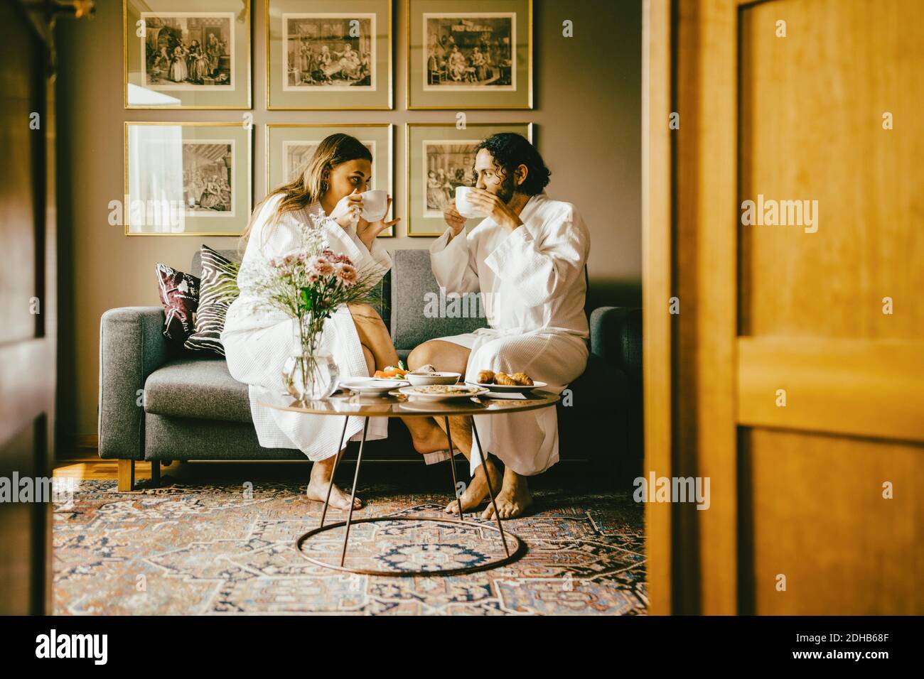 Paar in Bademänteln, die Kaffee trinken, während sie das Frühstück im Hotel genießen Stockfoto